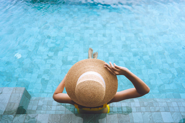Viaje de verano de vacaciones en el concepto tropical sureste. Vista trasera de la mujer asia en el complejo de piscina de lujo para relajarse y estilos de vida de bienestar spa.  - Foto, Imagen