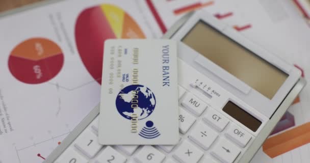 Kreditní karta leží na kalkulačce na papíře s grafy v úřadu. Účetnictví a moderní bankovní vybavení pro provádění velkých plateb za služby online - Záběry, video