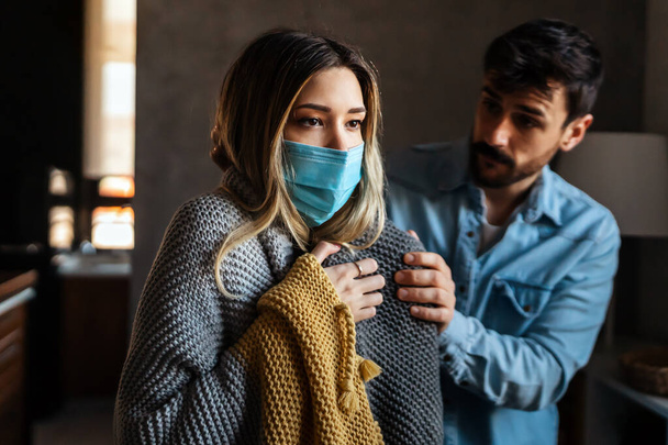 Young woman suffering with cold and flu, cancer. Husband taking care of his sick wife. Disease people concept. - Photo, Image