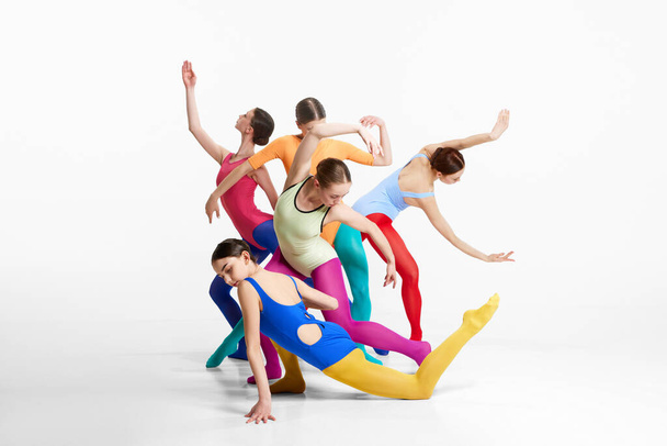 Group of artistic, young girls, ballerinas in multicolored clothes making performance, dancing against grey background. Concept of beauty, creativity, classic dance style, elegance, contemporary art - Photo, image