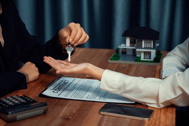 Агент по недвижимости передает ключ покупателю как символ владения после успешного завершения договора займа, воплощая в жизнь мечту о новом доме. Энтузиазм - Фото, изображение