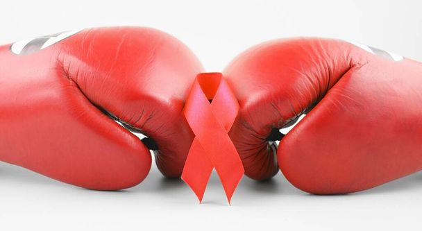 Ruban rouge avec gants de boxe, symbole de lutte. Journée mondiale du sida et Mois national de la sensibilisation au VIH, au sida et au vieillissement. - Photo, image