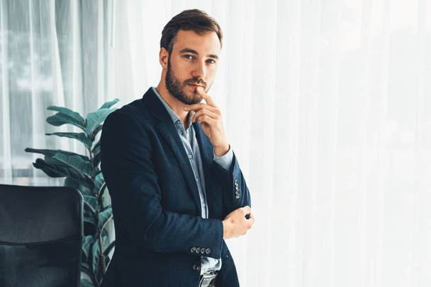 Handsome businessman in black suit stand confidently in his modern office portrait, deep in thought about business with pensive gazing expression, thinking strategically about his next move. Entity - Foto, imagen