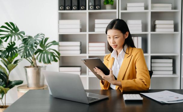 Businesswoman using tablet and laptop in office - Photo, image