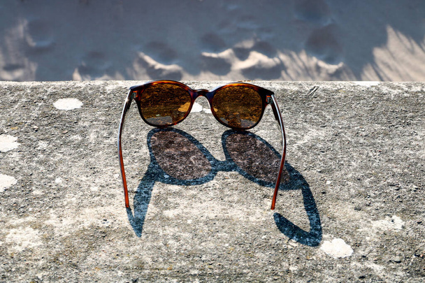 Gafas de sol en una pared de playa de hormigón en la tarde sol de primavera - Foto, imagen