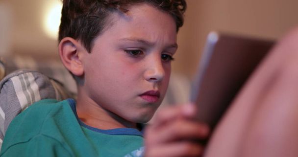 Young boy child using tablet device technology. Kid staring at screen at night - Zdjęcie, obraz