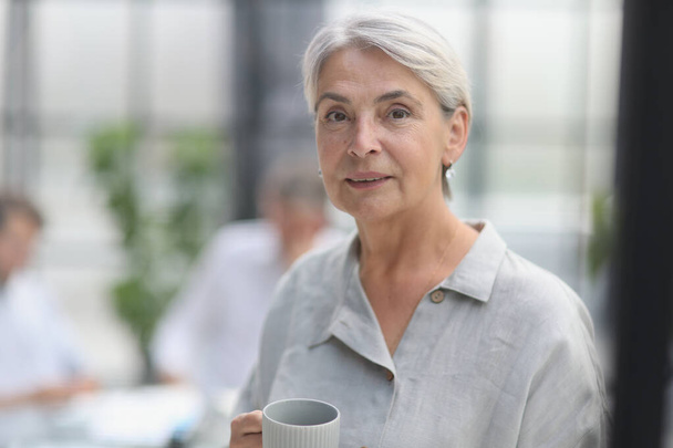 close-up mature woman holding a cup in the office. - Foto, Imagen