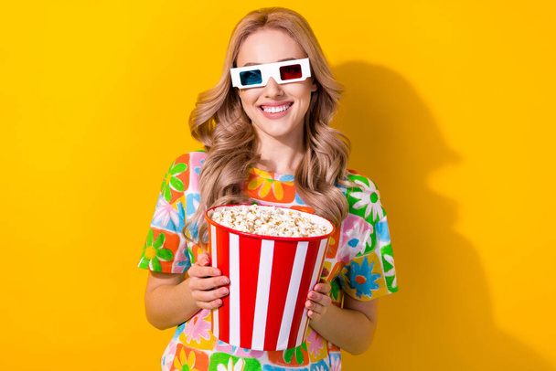 Portrait of adorable good mood woman wear flower print t-shirt hold popcorn watch interesting film isolated on yellow color background. - Fotó, kép