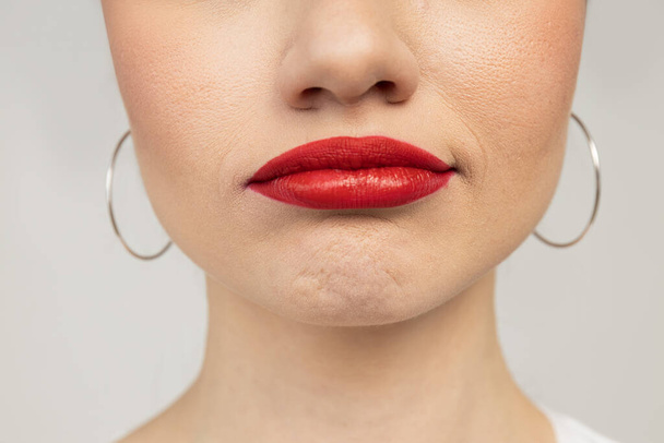 Onderkant van het gezicht van jonge vrouw met rode lippen, close up - Foto, afbeelding