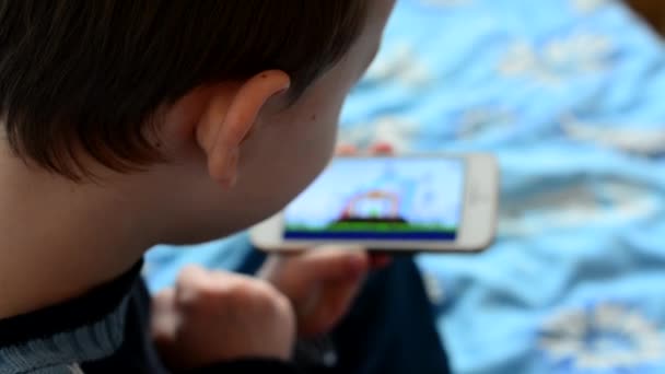 Kleine jongen speelt games op de smartphone - schot over de schouder - Video
