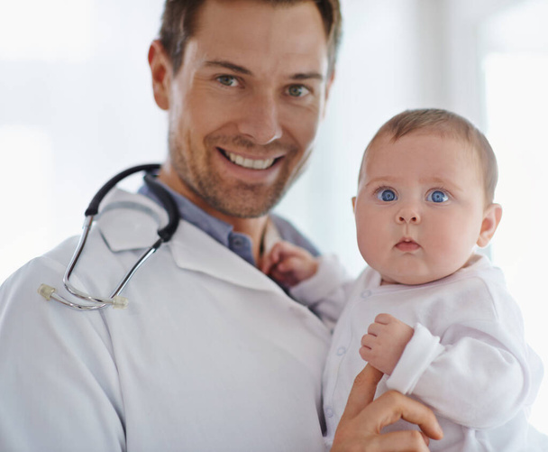 Portrait, happy pediatrician and holding baby in hospital for medical support and growth. Newborn kid face, man and pediatrics doctor in clinic, healthcare service or smile of trust for children. - Foto, Imagen