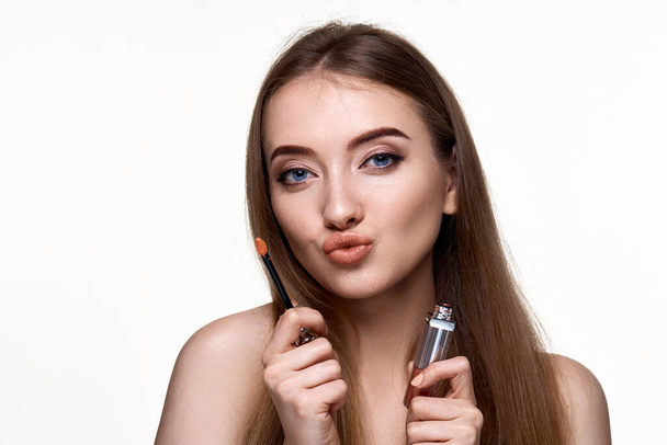 beautiful young woman with pouted lips holding lip gloss isolated on white background - Valokuva, kuva