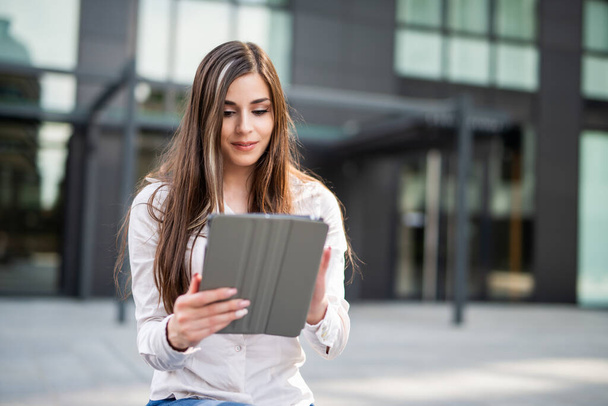 Smiling businesswoman using a digital tablet outdoor - Fotó, kép