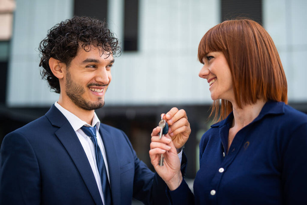 Businessman giving the keys of a new office to a businesswoman, real estate sale concept - Fotó, kép