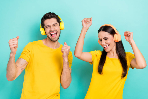 Portrait of crazy funky overjoyed youngsters listen music test high quality sound bass fists up wear yellow t-shirt isolated on cyan color background. - Foto, Imagem