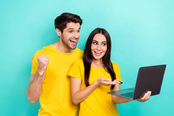 Photo of sweet excited married couple wear yellow t-shirts reading news device isolated turquoise color background. - Foto, immagini