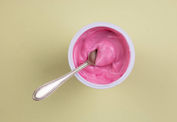 Pink red velvet flavour yogurt in plastic cup isolated on yellow pastel background with copy space - Foto, immagini