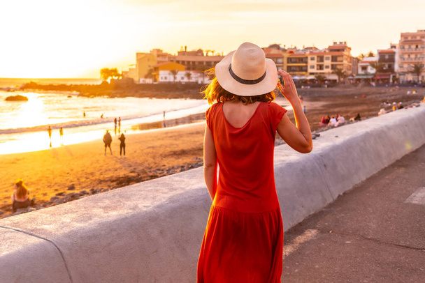 Туристична жінка на заході сонця з червоною сукнею на пляжі міста Валле - Ґран - Рей у Ла - Гомері (Канарські острови). - Фото, зображення