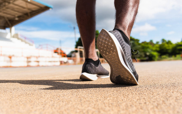 Asian young athlete sport runner black man wear feet active ready to running training at the outdoor on the treadmill line road for a step forward, healthy exercise workout, closeup back shoe - 写真・画像