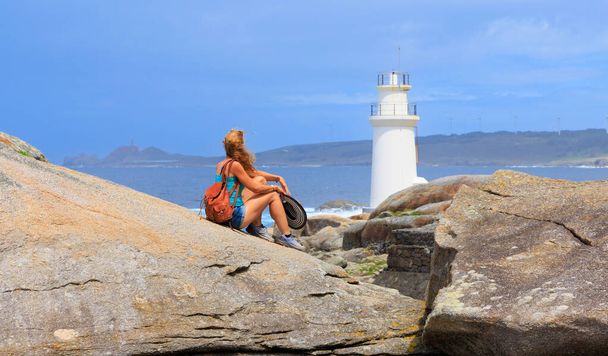 Traveler woman looking at lighthouse- Muxia in Spain - 写真・画像