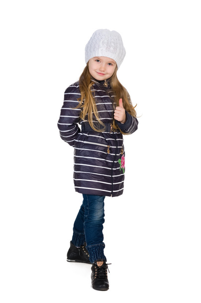 Little girl in a striped coat holds her thumb up - Foto, imagen