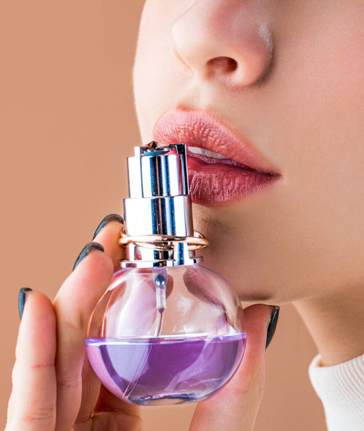 Sexy lips. Pink lip. Close up of sexy plump soft lips with dark red lipstick. Beautiful girl using perfume. Woman with bottle of perfume. Woman presents perfumes fragrance. - Фото, изображение