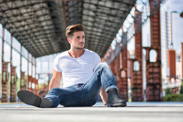 Handsome man in city setting, a former industrial environment, under a huge metal structure - Fotoğraf, Görsel