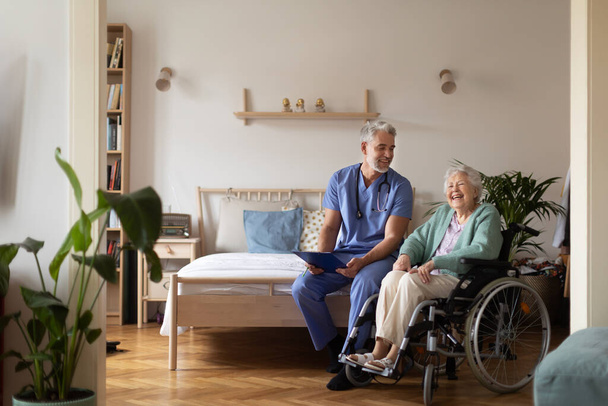 Caregiver doing regular check-up of senior client in her home. - Foto, imagen