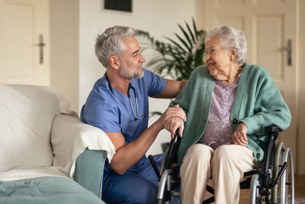 Caregiver doing regular check-up of senior client in her home. - Фото, изображение