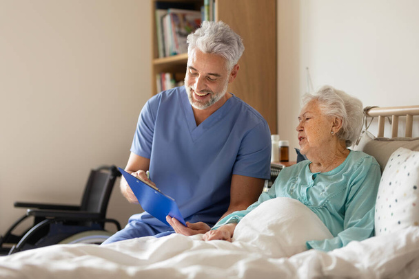 Caregiver doing regular check-up of senior client in her home. - Foto, Imagen