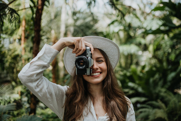 Portrait of a young woman with camera in jungle. - Foto, afbeelding