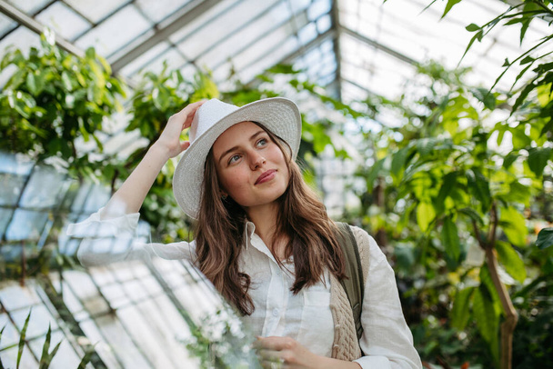 Portrait of young happy woman in a greenhouse. - Фото, зображення