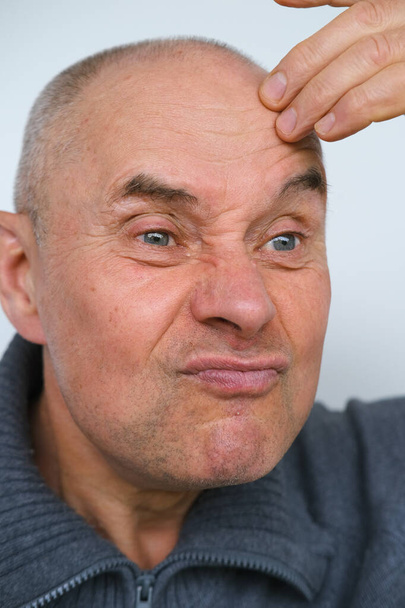 close-up male face makes negative grimaces aggression, mature man, senior 60 years old with foolish threatening facial expression, concept mental human health, optimism in adulthood, midlife crisis - Фото, зображення