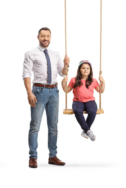 Full length portrait of a father standing next to a daughter on a swing isolated on white background - Valokuva, kuva