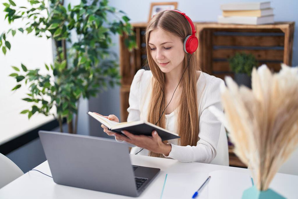 Young caucasian woman reading book listening to music studying at home - Photo, image