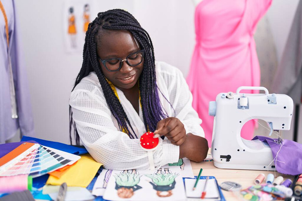Femme afro-américaine tailleur souriant confiant épinglette tenue au magasin de tailleur - Photo, image