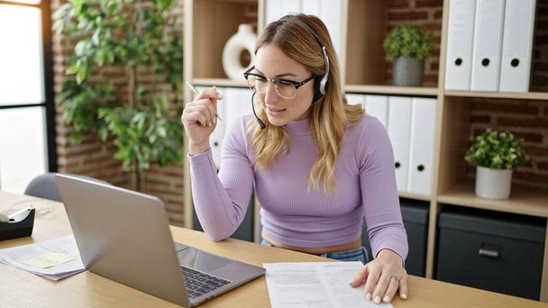 Młoda piękna latynoska kobieta biznes pracownik noszenie słuchawki pisząc dokument w biurze - Zdjęcie, obraz