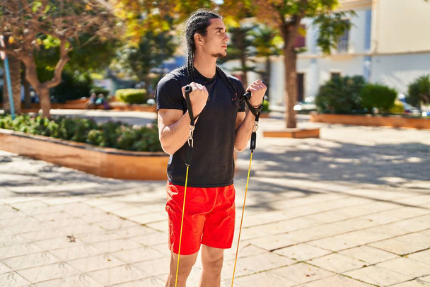 Young man training with elastic band at park - Foto, Imagen