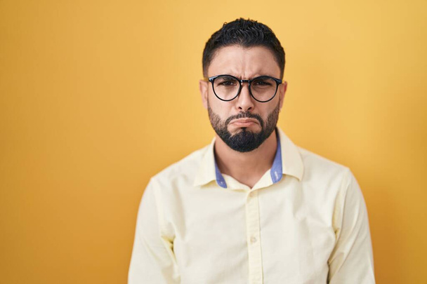 Jeune homme hispanique portant des vêtements et des lunettes de travail déprimé et inquiet pour la détresse, pleurer en colère et peur. triste expression.  - Photo, image