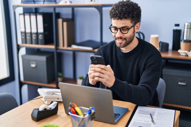 Молодой арабский бизнесмен использует смартфон, работающий в офисе - Фото, изображение