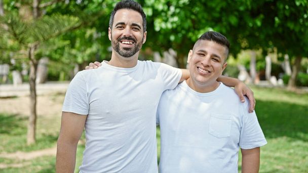 Due uomini sorridenti fiduciosi che si abbracciano al parco - Foto, immagini