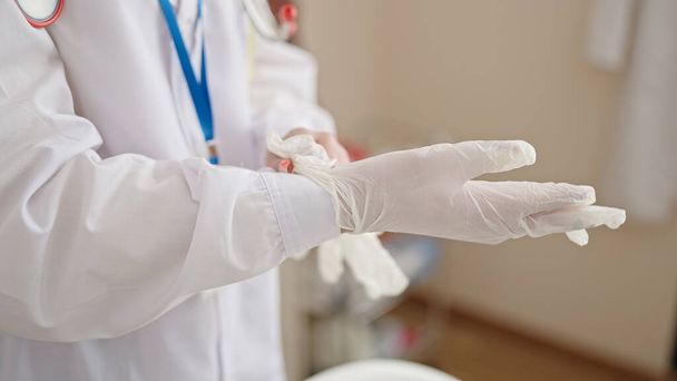 Young blonde woman doctor wearing gloves at clinic - Photo, image