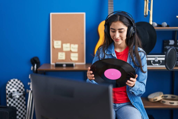 Fiatal spanyol lány művész zenét hallgat kezében vinyl lemez a zenei stúdióban - Fotó, kép