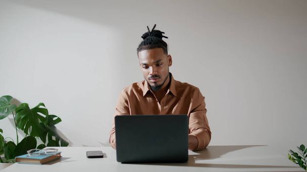 İş yerinde klavye yazan modern bir öğrenci. Ofiste ekranı izleyen odaklanmış bir adam. Afrika kökenli Amerikalı iş adamı e-posta okuyup proje konularını düşünüyor. Evde bilgisayarda çalışan düşünceli bir adam. - Fotoğraf, Görsel