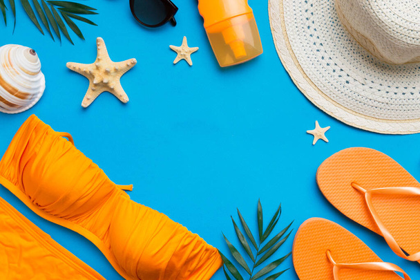 Woman swimwear and beach accessories flat lay top view on colored background Summer travel concept. bikini swimsuit, straw hat and seasheels. Copy space Top view. - Foto, afbeelding