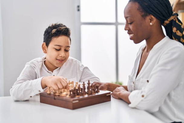 African american mother and son playing chess game sitting on table at home - Foto, immagini