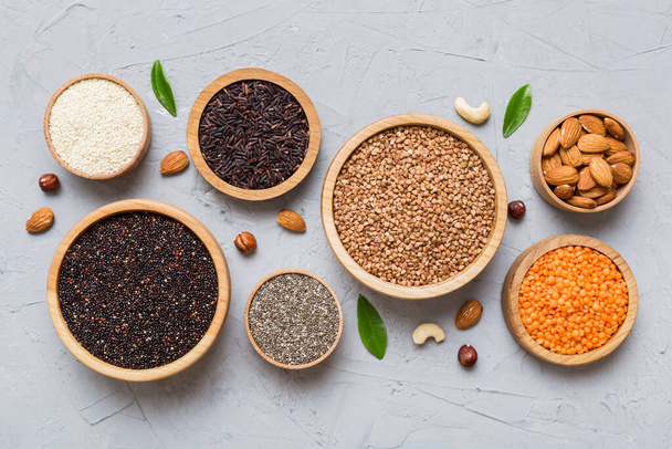 Various superfoods in smal bowl on colored background. Superfood as rice, chia, quinoa, lentils, nuts, sesame seeds, almonds. top view copy space. - Photo, Image