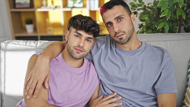 Zwei Männer umarmen sich zu Hause mit entspanntem Gesichtsausdruck - Foto, Bild