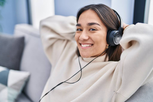 Jonge Spaanse vrouw die thuis naar muziek zit te luisteren - Foto, afbeelding