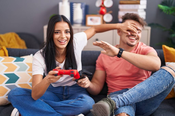 Man and woman couple playing video game sitting on sofa at home - Foto, afbeelding